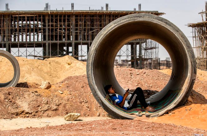 Un ouvrier se repose à l'intérieur d'un tuyau en béton tout en se protégeant du soleil sur le chantier de construction du nouveau mégaprojet de la capitale administrative égyptienne, à 45 km à l'est du Caire, le 3 août 2021.