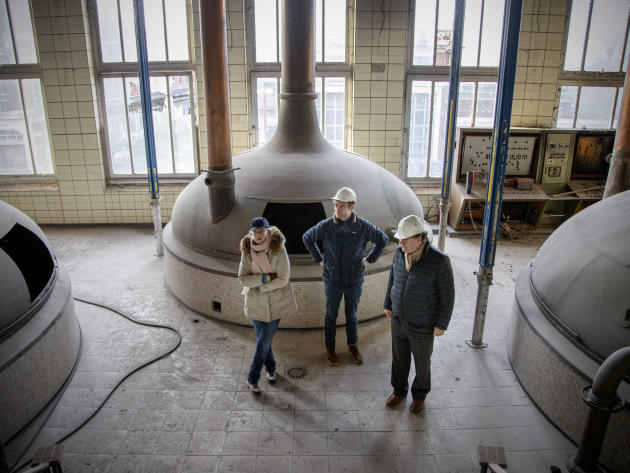 Henry Motte (au centre) et ses parents, François et Anne-Catherine, dans la salle de brassage historique, avec ses trois cuves de fermentation, à Armentières (Nord), le 7 décembre 2021.