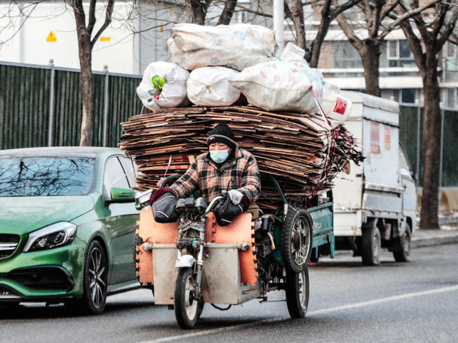 Un travailleur migrant transportant du carton recyclable, à Pékin, le 20 janvier 2022.