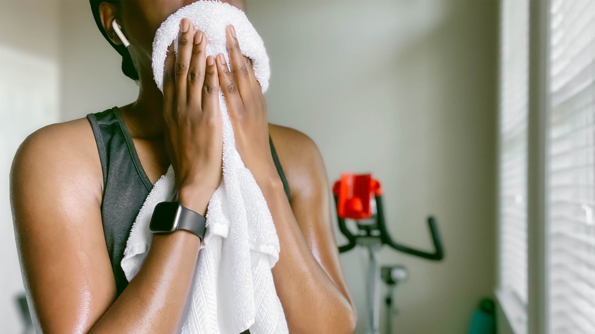 Les vélos d'exercice brûlent-ils la graisse du ventre?  Image d'une femme utilisant une serviette absorbante après avoir utilisé un vélo d'exercice