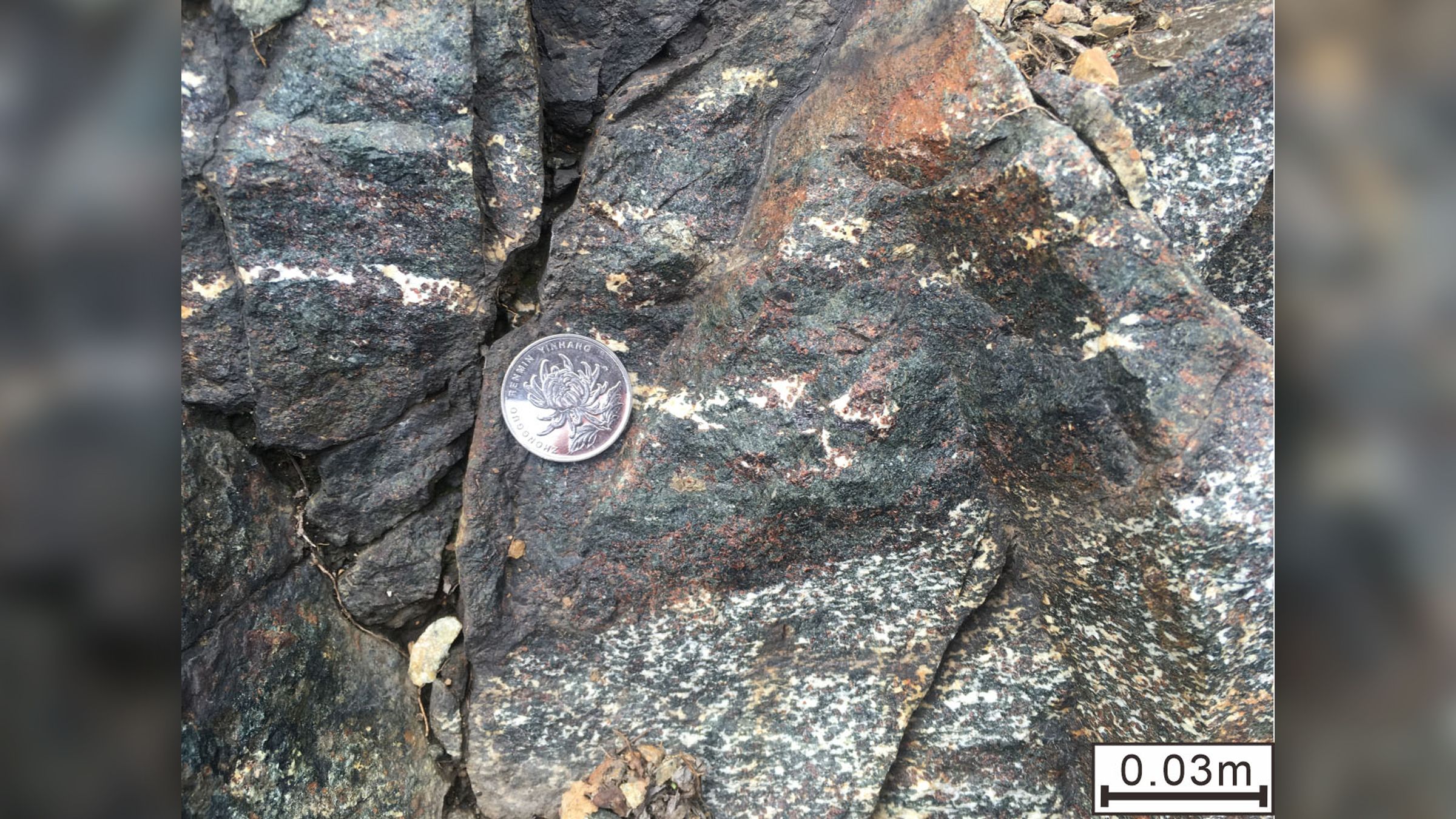 Une formation rocheuse montrant de l’éclogite (couche sombre, avec du grenat rouge et du pyroxène vert) de l’éon archéen intercalé avec du métagabbro grenat de Shangying, en Chine.