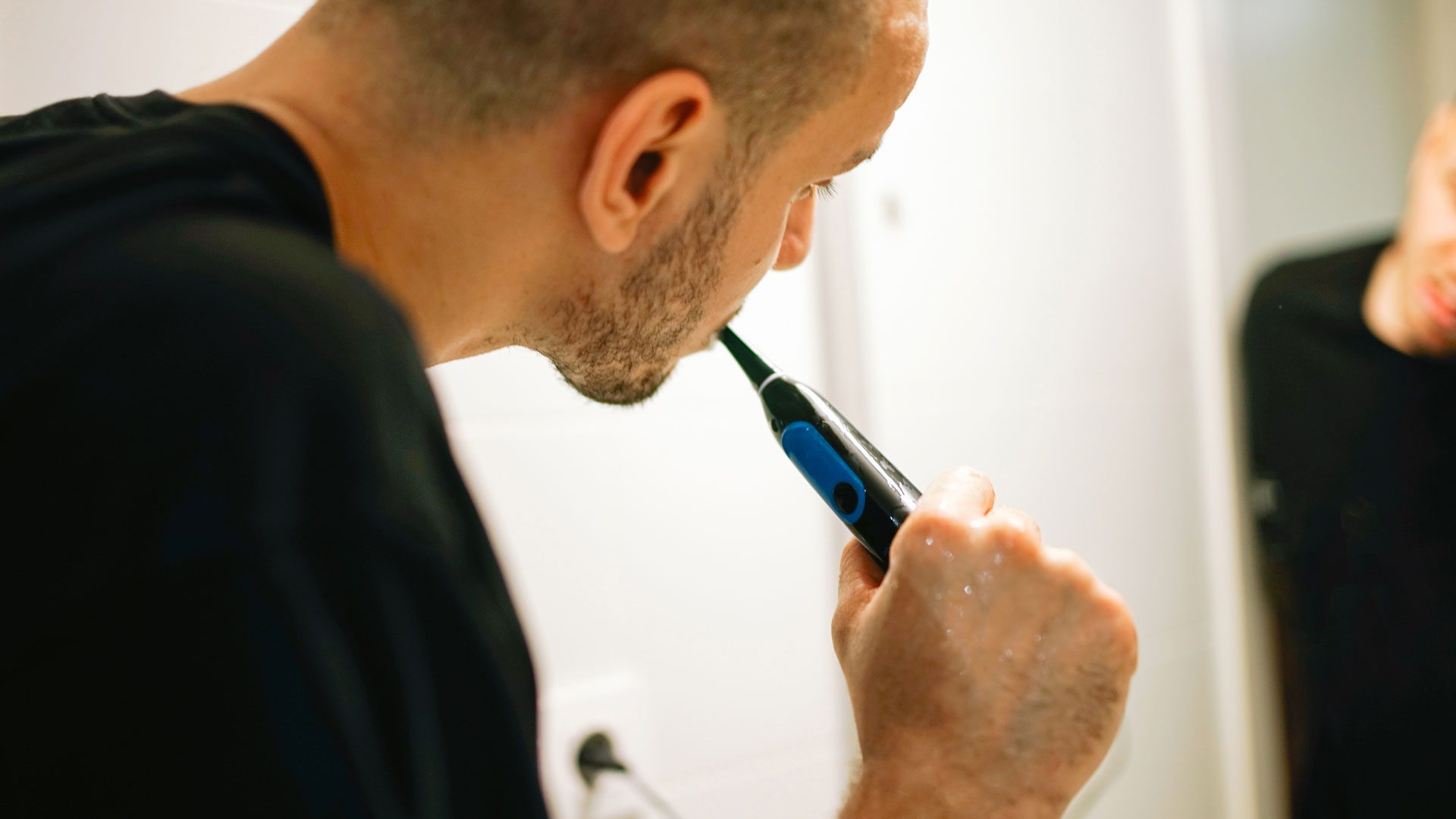 L'image montre un homme se brosser les dents dans un miroir