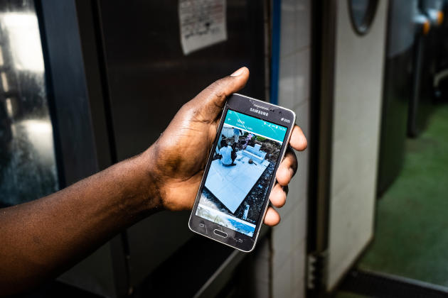 Dieuvenor, lave-vaisselle au Café du Commerce, montre la photo des funérailles de sa mère qui ont eu lieu la semaine précédente en Haïti.  Ne pouvant être présent, il a demandé à un ami de confiance de le représenter.  A Paris, en juin 2022.