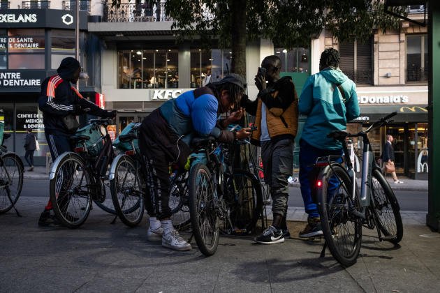 Place de Clichy, dans le 17e arrondissement de Paris, plusieurs hommes âgés de 20 à 40 ans, Ivoiriens, Guinéens, Afghans ou Algériens, attendent de partir livrer pour des plateformes de livraison de repas comme Uber Eats.  Ici, le 22 septembre 2022.