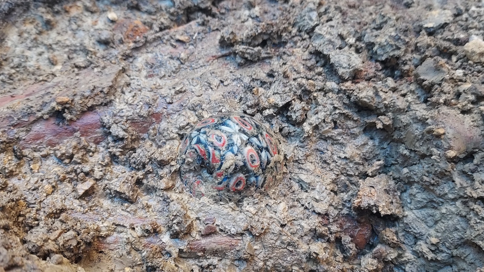 Une grande perle de verre millefiori tachetée de différentes couleurs de verre fusionnées trouvées sur le lieu de sépulture.