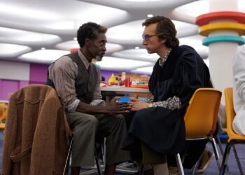 L'image peut contenir une personne assise, des vêtements, des vêtements, des meubles, une chaise et Don Cheadle