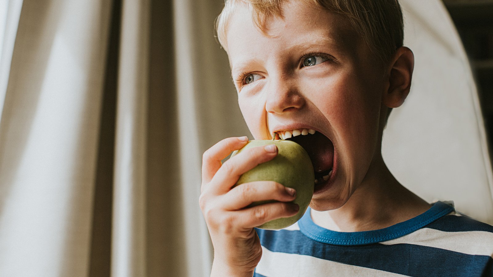 Jeune garçon mordant dans une pomme verte