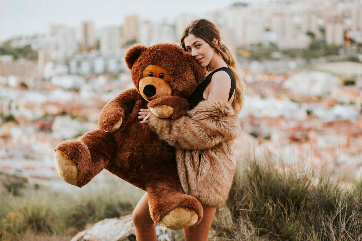 femme embrassant un ours en peluche dans la rue