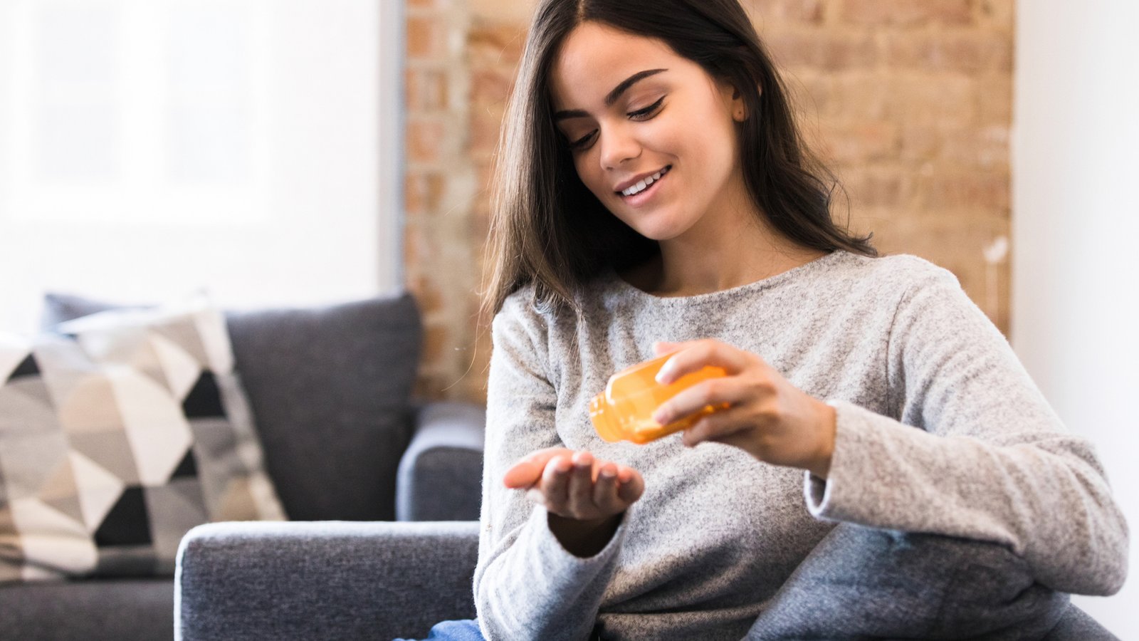 femme assise sur son canapé prenant un supplément de magnésium