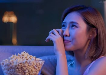 Une jeune femme pleure en regardant un film très émouvant avec du pop-corn la nuit