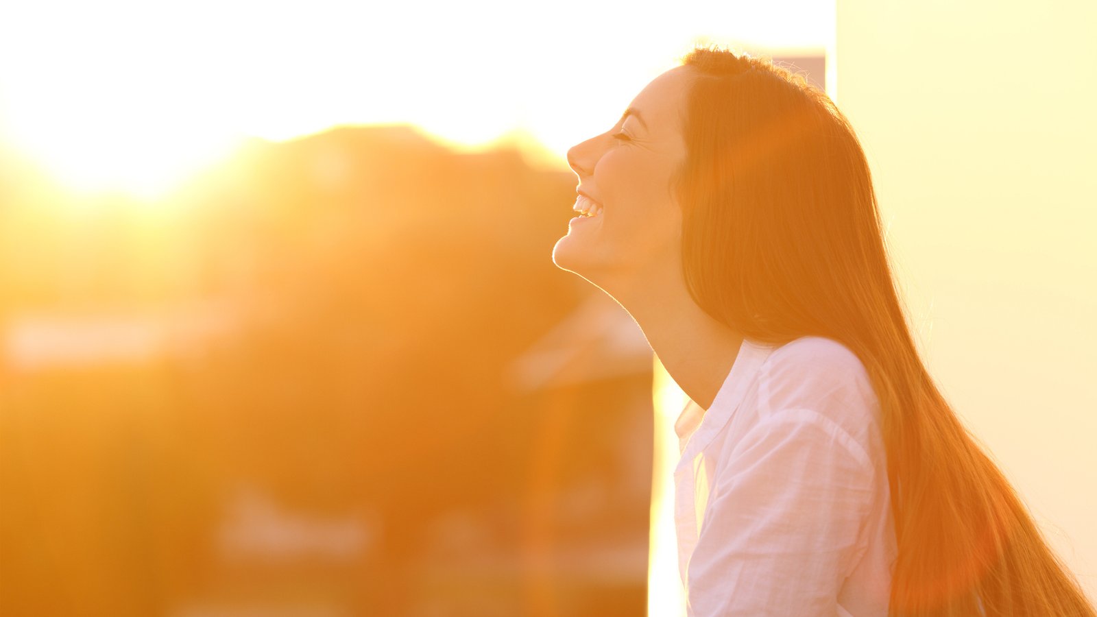 Portrait de vue de côté d'une femme heureuse respirant l'air frais profond au coucher du soleil dans un balcon de maison