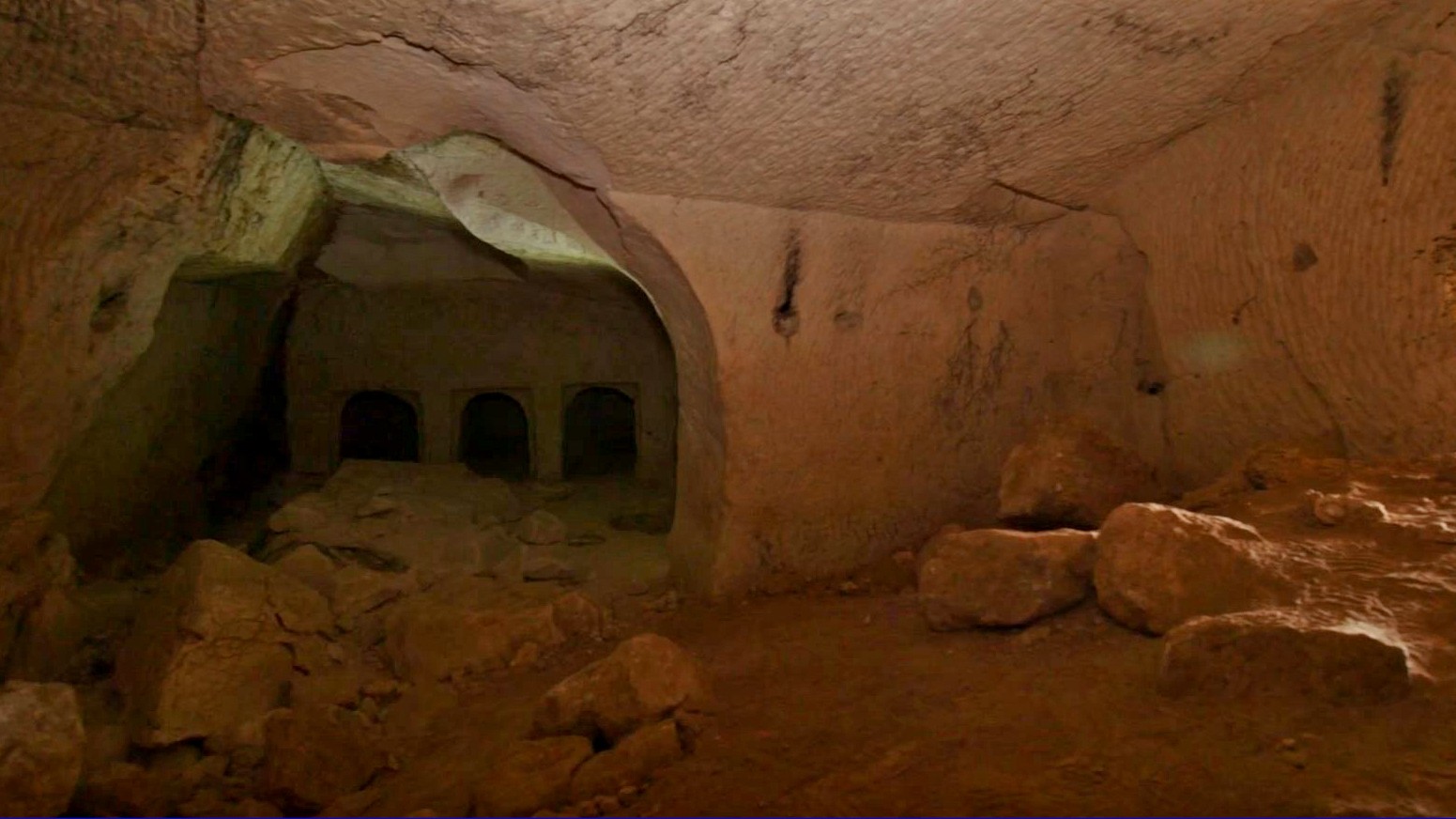 Ici, nous voyons l'intérieur de la grotte de Salomé.  Il y a une entrée circulaire sur la gauche qui mène à trois portes rectangulaires.