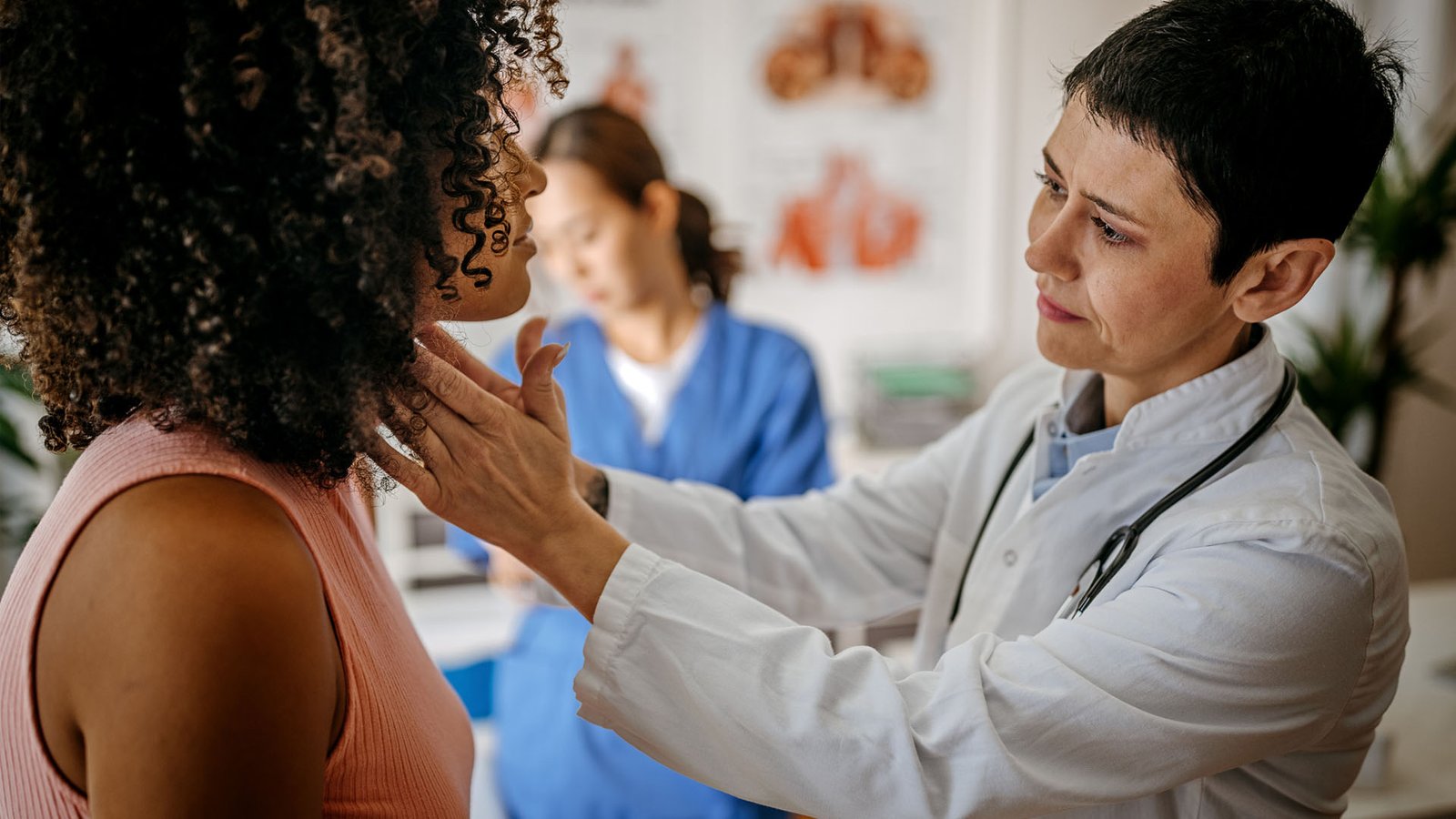 Femme médecin examinant une patiente dans son cabinet médical tandis qu'une infirmière écrit des informations sur le patient