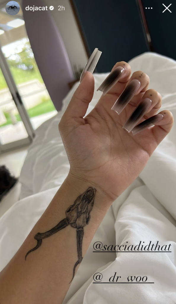 Le chat Doja a un nouveau tatouage et il donne Poignet et main gauches du chat Doja montrant un tatouage de crâne d'antilope et une longue manucure en dégradé