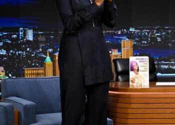 michelle obama souriant avec des tresses de boîte de déesse coiffées en queue de cheval haute