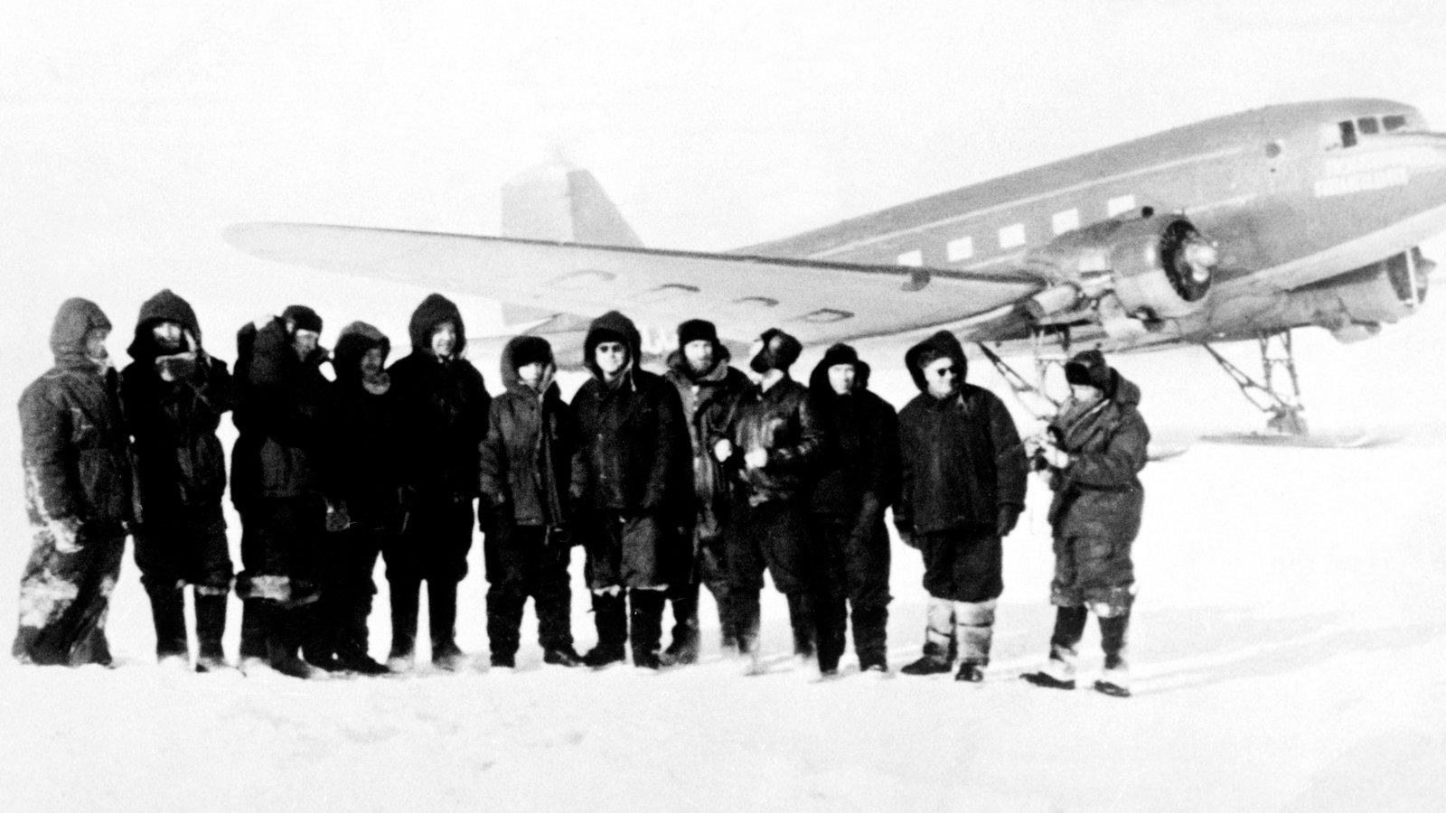 Hommes debout près d'un avion en Antarctique en 1957