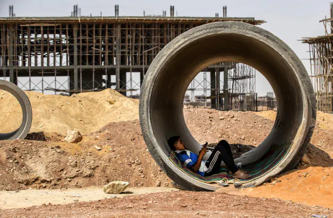 Un ouvrier se repose à l'intérieur d'un tuyau en béton tout en se protégeant du soleil sur le chantier de construction du nouveau mégaprojet de la capitale administrative égyptienne, à 45 km à l'est du Caire, le 3 août 2021.