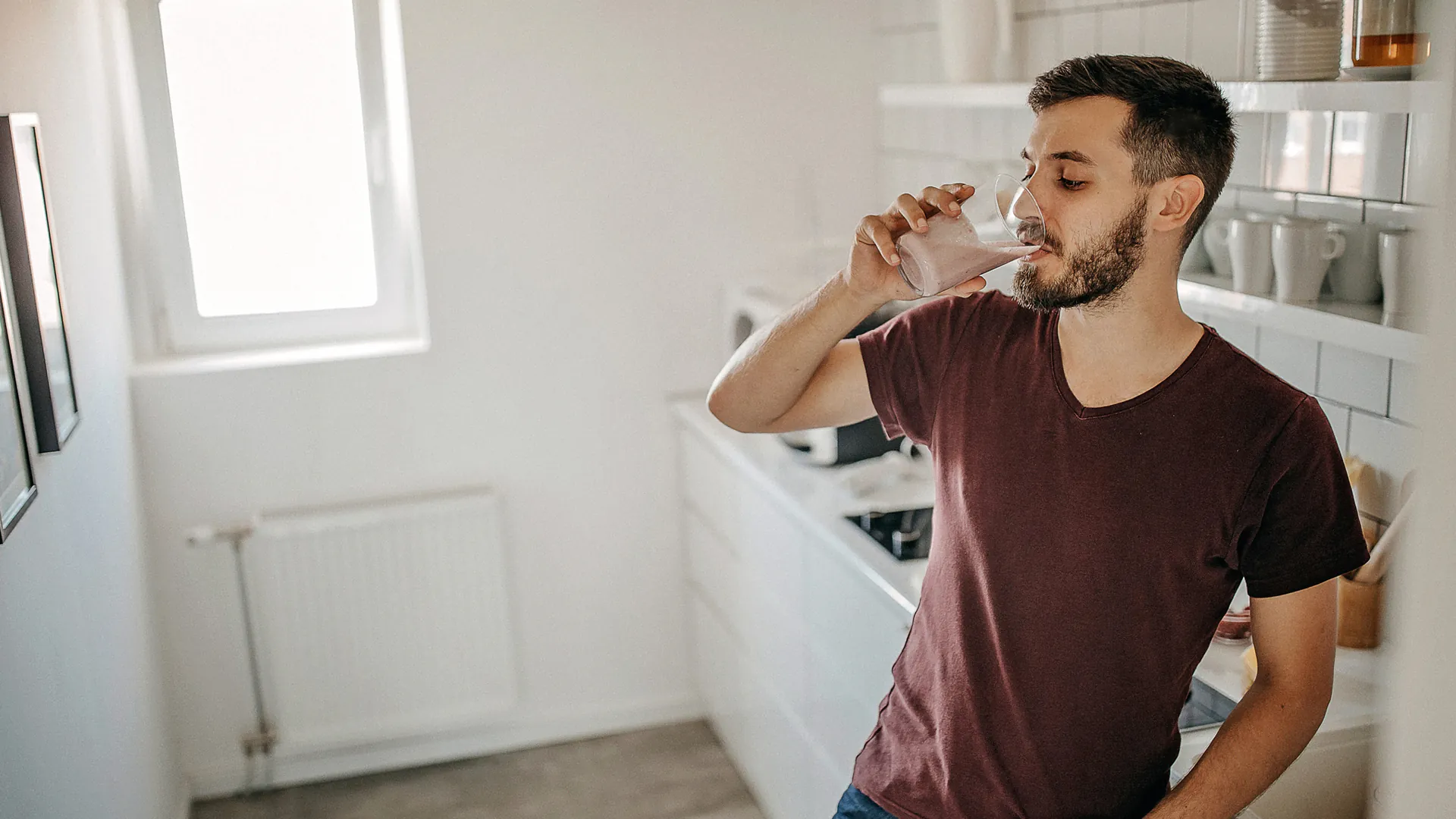 homme buvant un shake substitut de repas dans sa cuisine