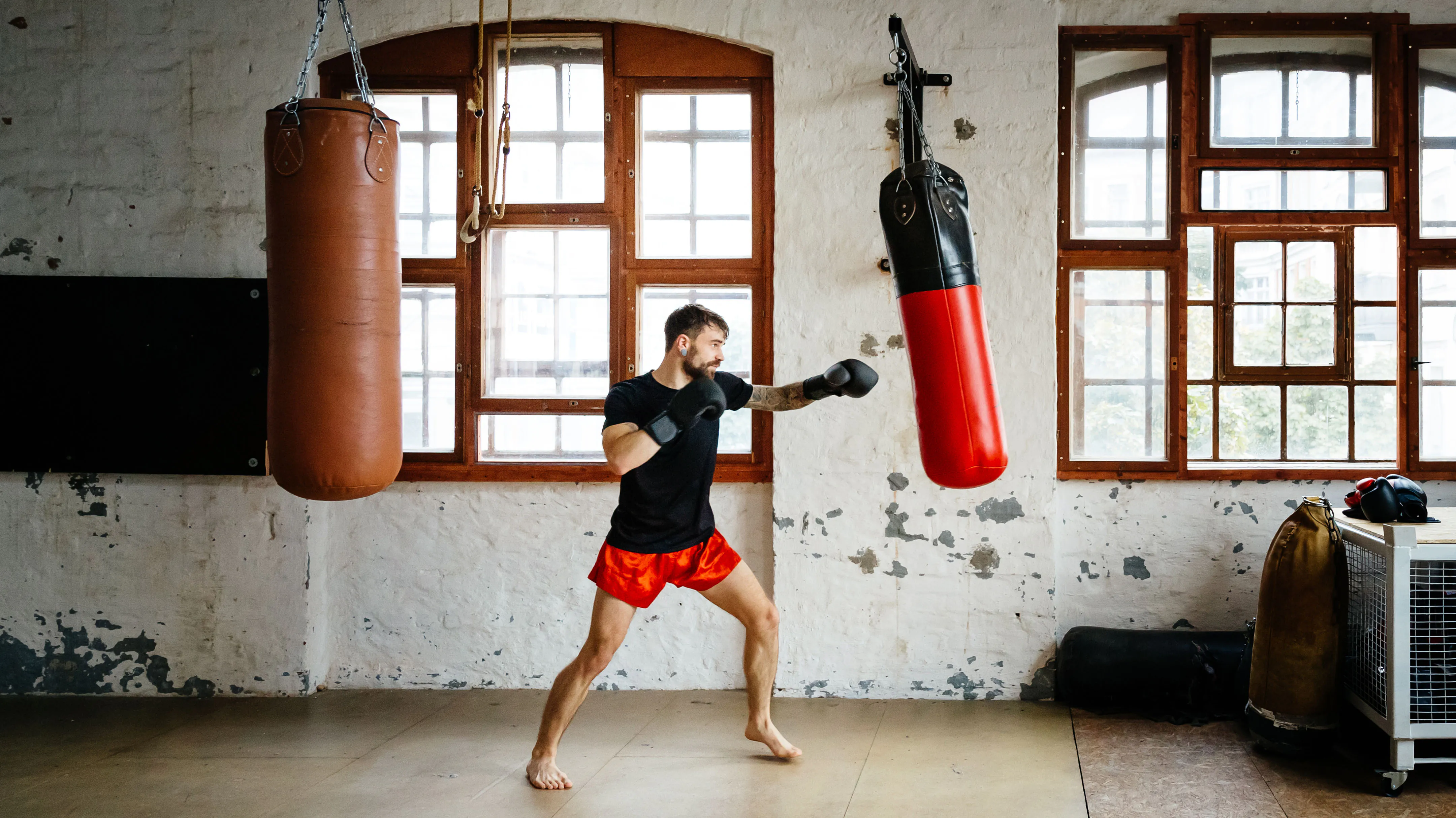 Boxeur masculin s'entraînant sur des sacs de sable dans une salle de sport