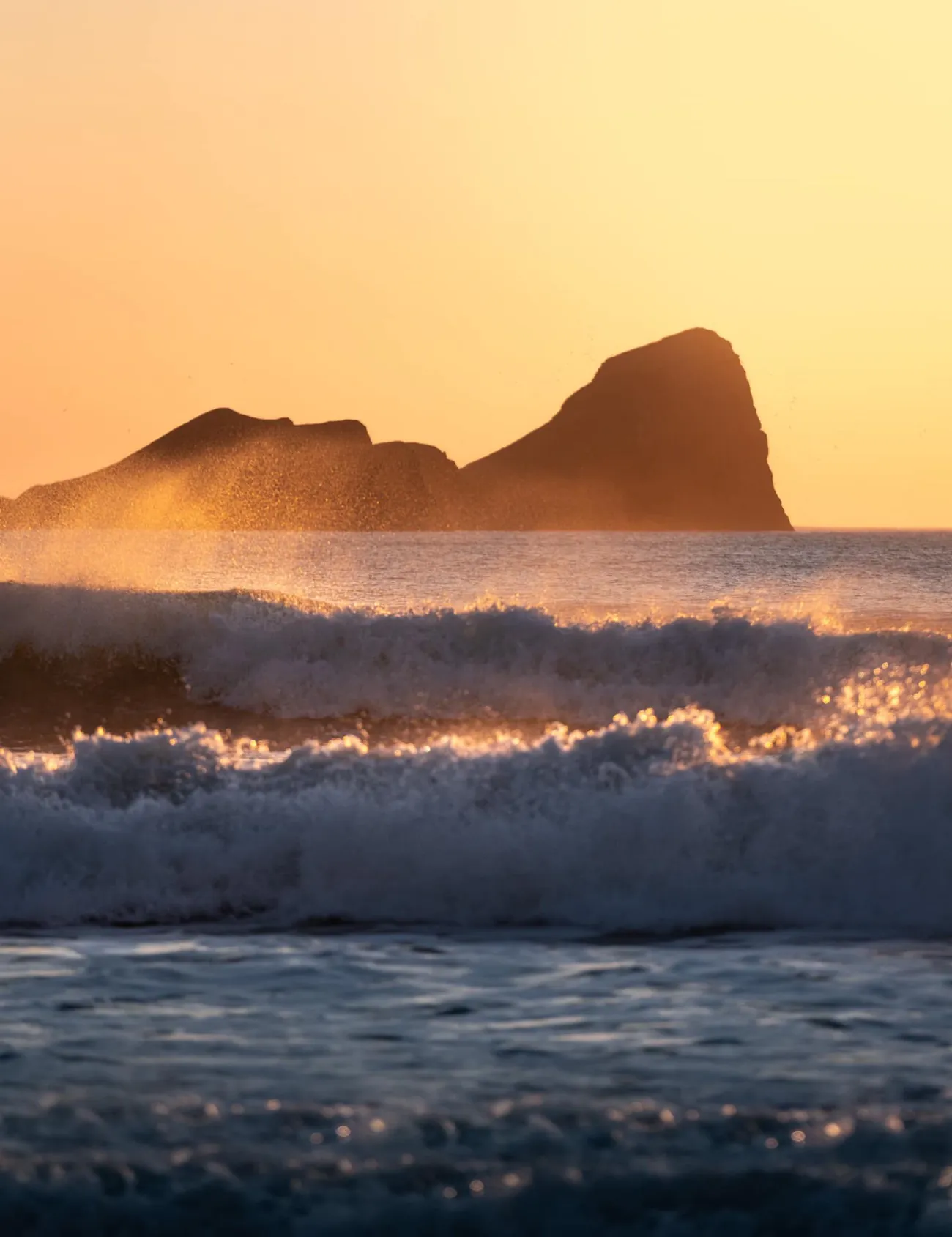 Photo de grosses vagues qui se brisent au coucher du soleil.