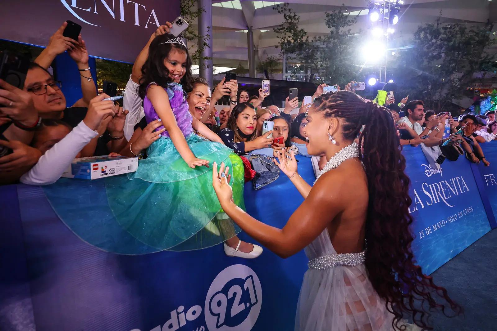 halle bailey avec une longue queue de cheval loc bouclée sur le point d'embrasser un jeune enfant