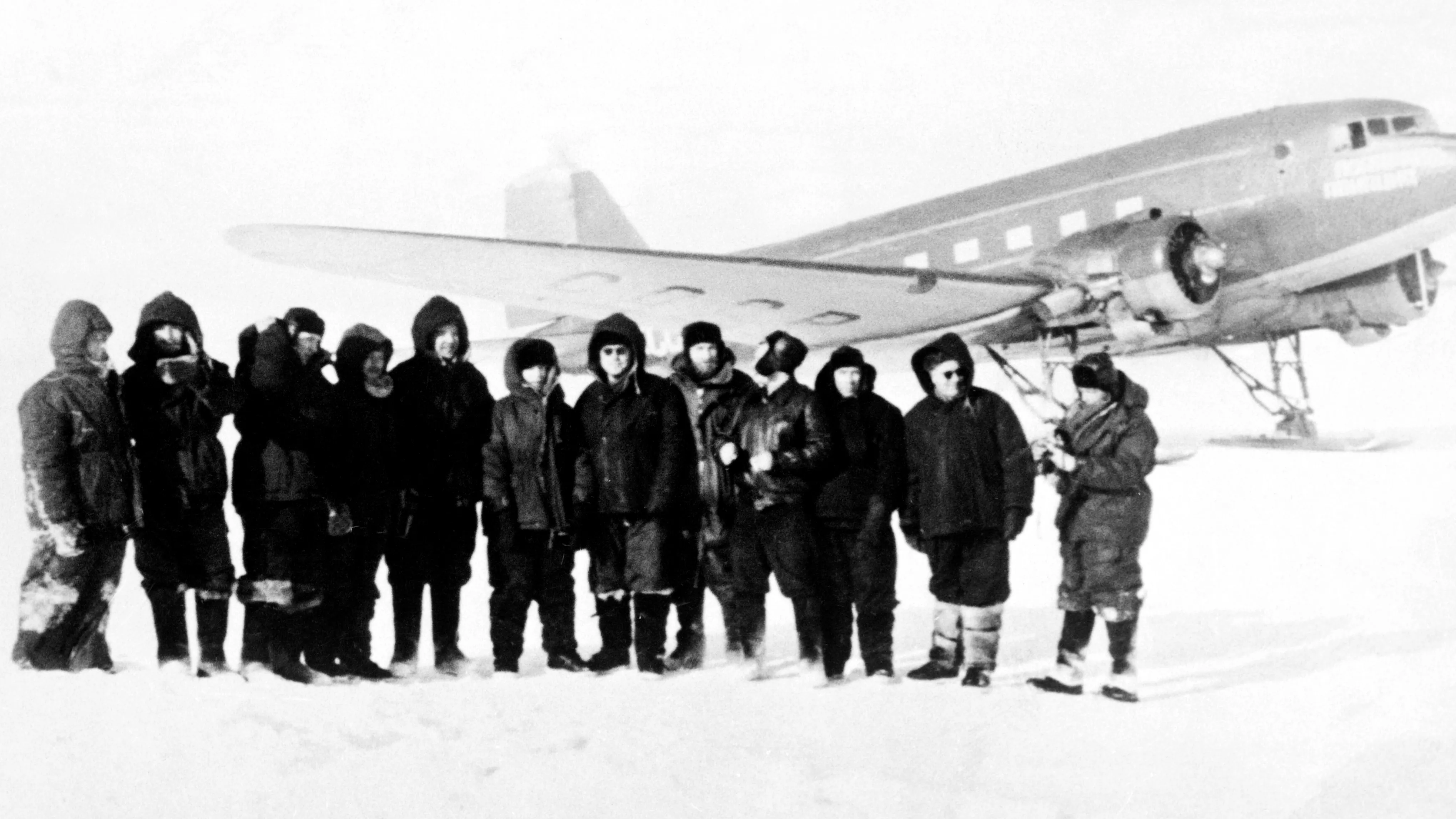 Hommes debout près d'un avion en Antarctique en 1957