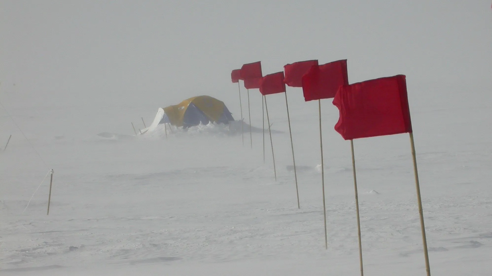 Un igloo sur un plateau glacé de l'Antarctique avec des drapeaux rouges