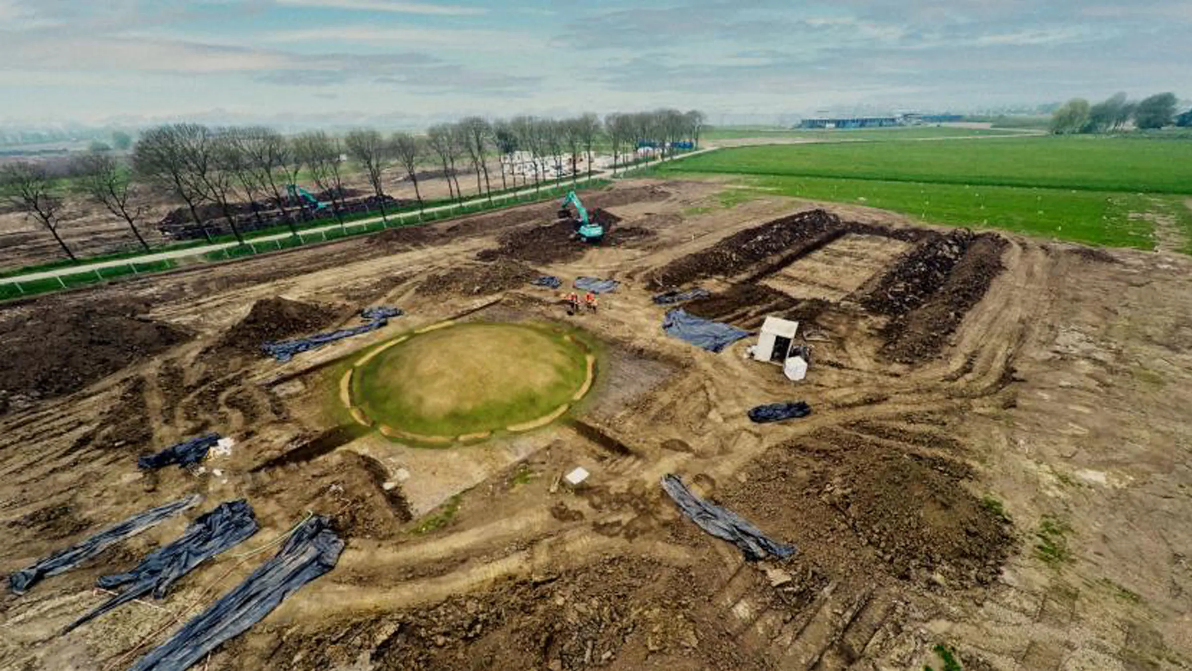 Une vue à vol d'oiseau du site d'excavation avec le grand tumulus funéraire mis en évidence par une superposition d'herbe virtuelle.
